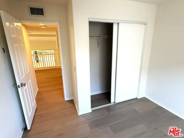 a view of a hallway with wooden floor and a kitchen