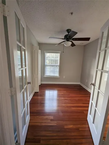 a view of an empty room with wooden floor and window