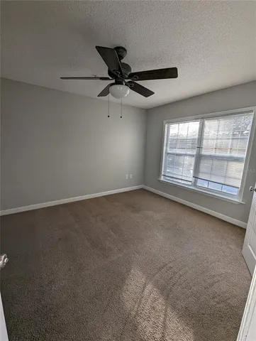an empty room with windows and ceiling fan