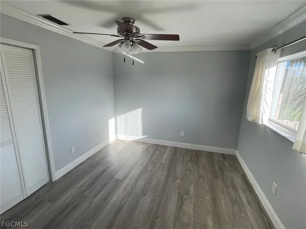 an empty room with wooden floor fan and windows