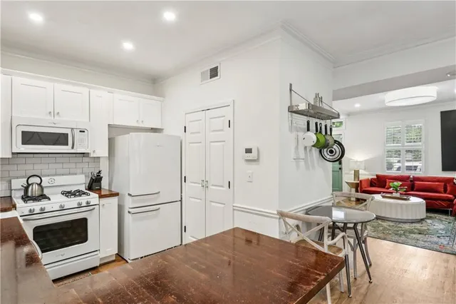 a kitchen with stainless steel appliances granite countertop a stove a refrigerator and a dining table with wooden floor