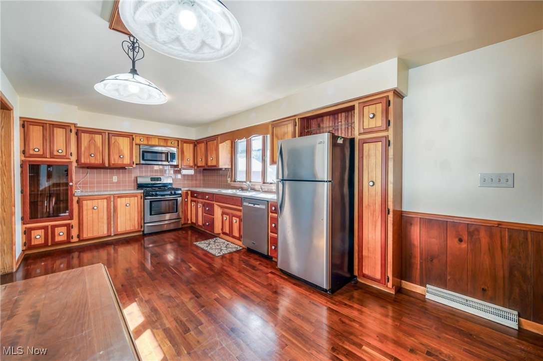 3210 Oser Road Norton, OH 44203 - Photo 20 of 47 Kitchen featuring appliances with stainless steel finishes, sink, backsplash, dark hardwood / wood-style flooring, and hanging light fixtures
