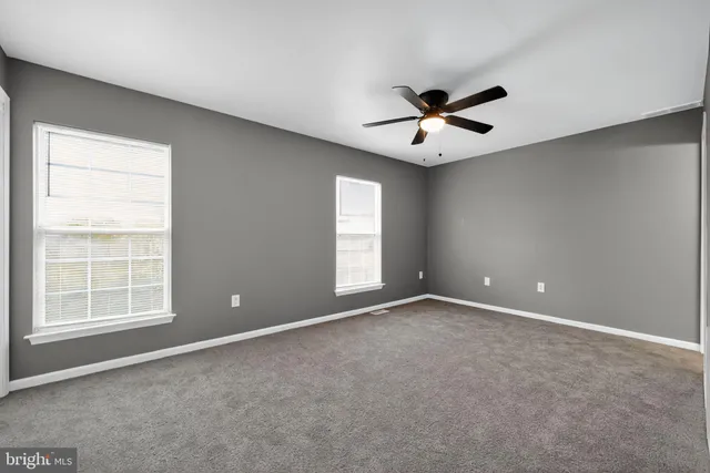 an empty room with windows and a ceiling fan