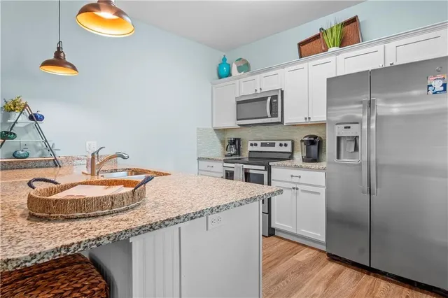 a kitchen with stainless steel appliances granite countertop a sink a stove and a wooden floors