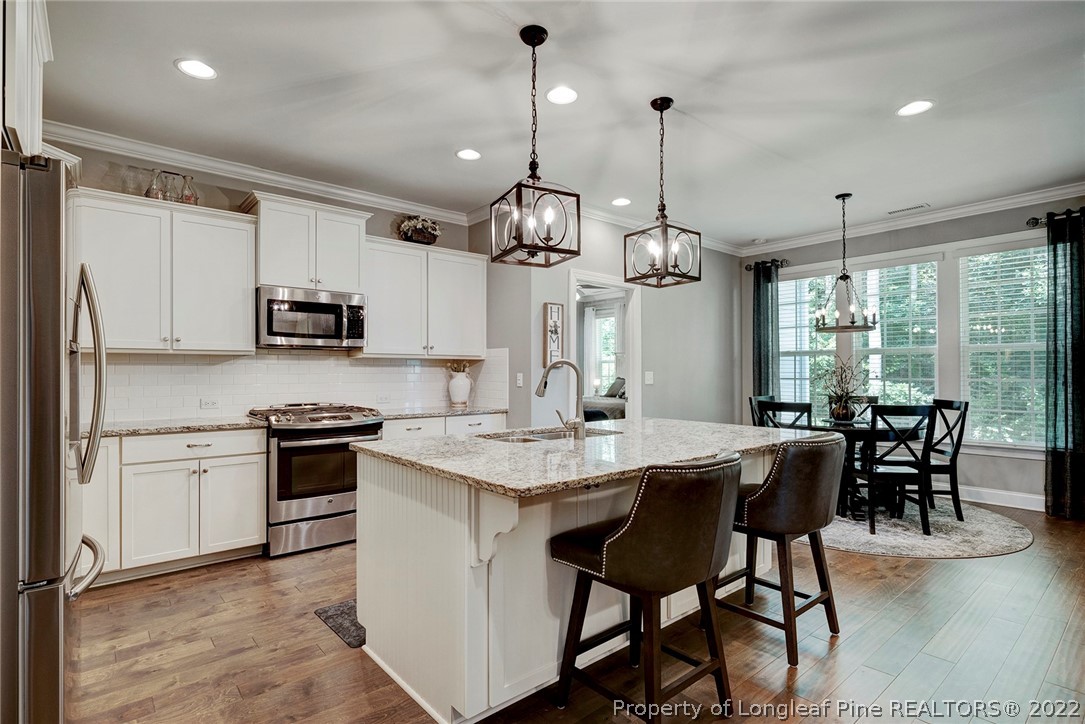4139 Olde Judd Drive Willow Spring, NC 27592 - Photo 15 of 42 a kitchen with stainless steel appliances granite countertop a stove a refrigerator a kitchen island a table and chairs