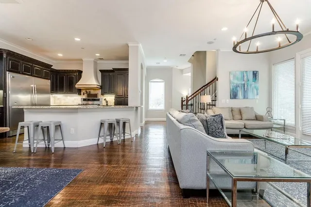 a living room with furniture kitchen view and a wooden floor