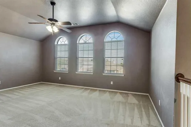 an empty room with windows and fan