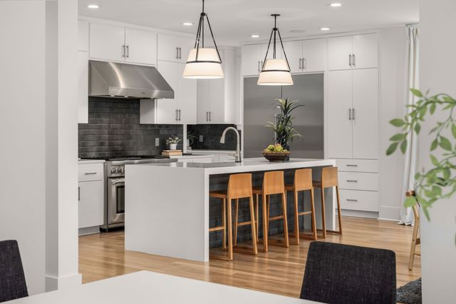 a kitchen with stainless steel appliances kitchen island granite countertop a refrigerator a sink a stove and a wooden floors