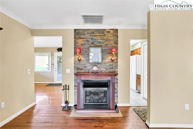 a view of an empty room with wooden floor and a fireplace