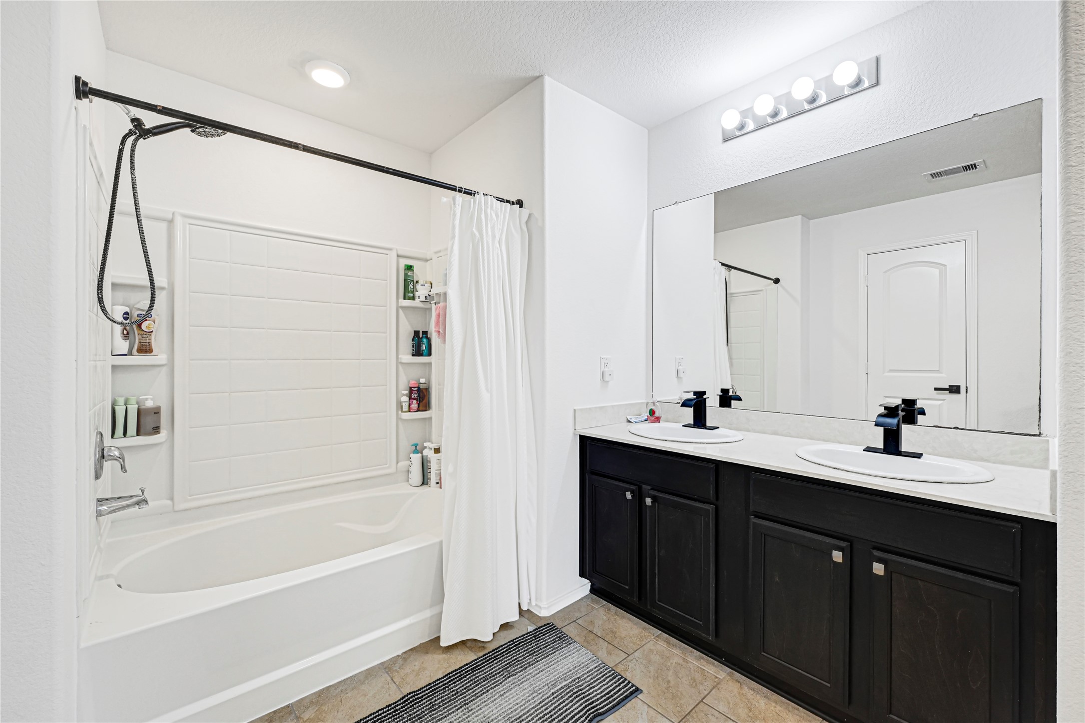 23343 Dukes Run Drive Spring, TX 77373 - Photo 12 of 21 a bathroom with a double vanity sink a large mirror and a bathtub