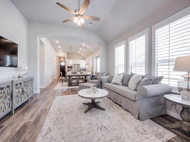 a living room with furniture a flat screen tv and a large window