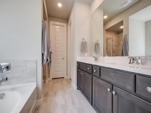 a spacious bathroom with a tub sink mirror and shower
