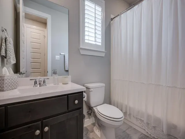a bathroom with a granite countertop sink toilet and mirror