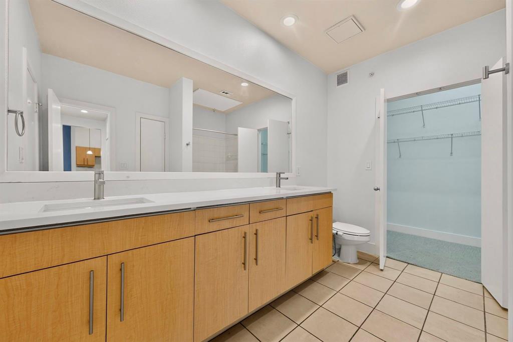 4414 Cedar Springs Road, Unit 318 Dallas, TX 75219 - Photo 25 of 40 Bathroom featuring a dual vanity with light wood-finish cabinetry, white countertop, and integrated sinks