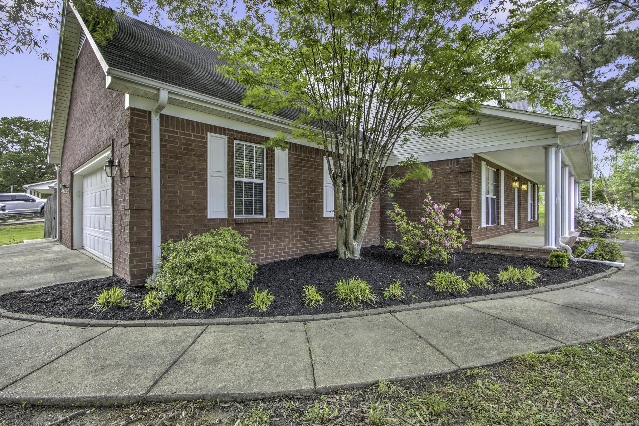 161 Shiloh Road Brighton, TN 38011 - Photo 38 of 38 View of home's exterior featuring an attached garage, brick siding, driveway, and covered porch