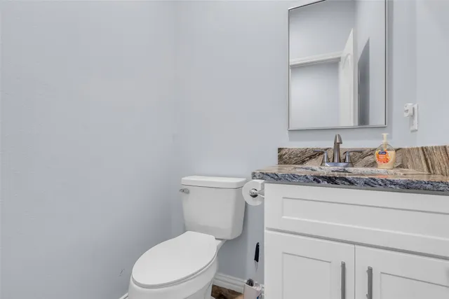 a bathroom with a granite countertop toilet sink and mirror