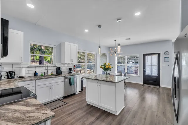 a kitchen with stainless steel appliances a sink dishwasher a stove a refrigerator cabinets and wooden floor