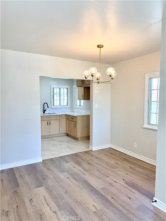 an empty room with wooden floor and kitchen view