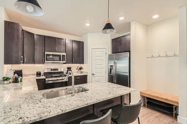 a kitchen with stainless steel appliances granite countertop a stove refrigerator and a sink
