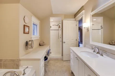 a bathroom with a sink double vanity granite tub shower and a mirror