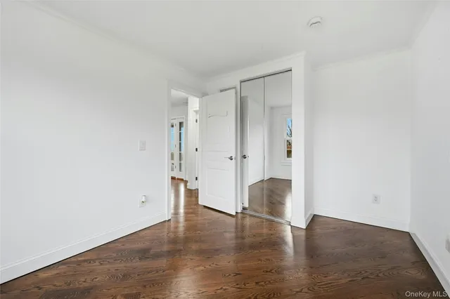 a view of an empty room with wooden floor and windows