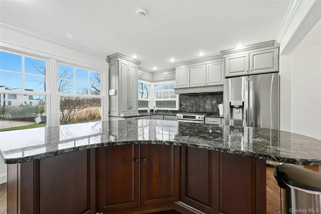 a kitchen with stainless steel appliances granite countertop a refrigerator a stove and a sink with wooden cabinets