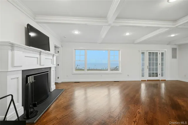 a view of an empty room with wooden floor fireplace and a window