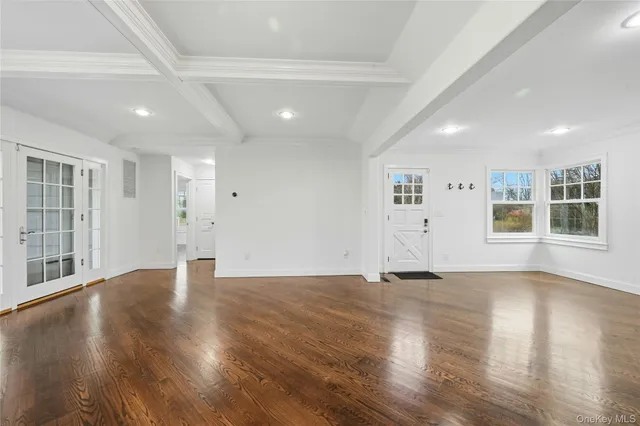 a view of an empty room with wooden floor and windows