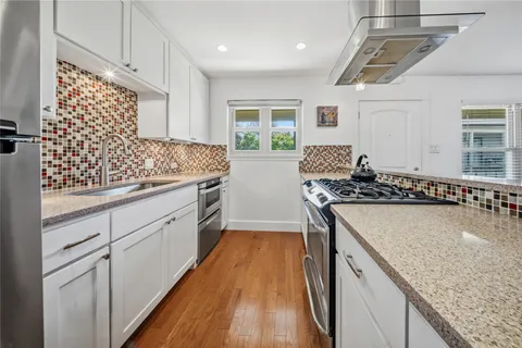 a kitchen with stainless steel appliances granite countertop a stove a sink and a refrigerator
