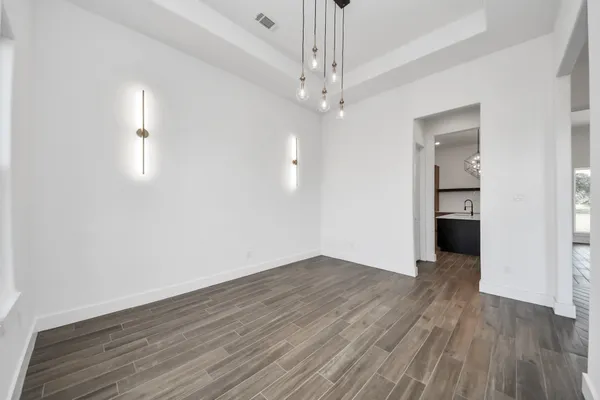 an empty room with wooden floor chandelier and windows