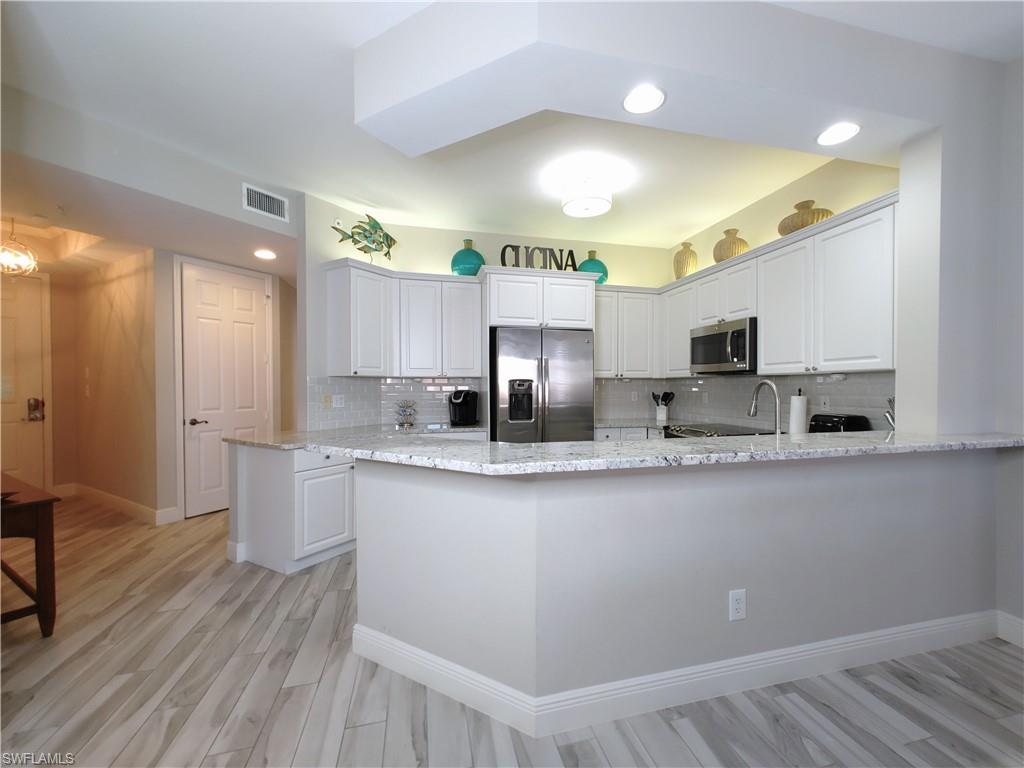 400 Flagship Drive, Unit 501 Naples, FL 34108 - Photo 11 of 38 a kitchen with stainless steel appliances a sink stove and cabinets