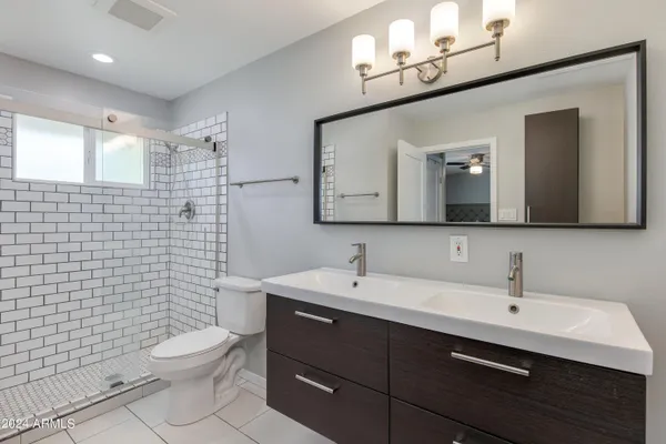 a bathroom with a toilet a sink a mirror a shower a vanity and mirror