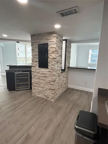 a view of an empty room with wooden floor and windows