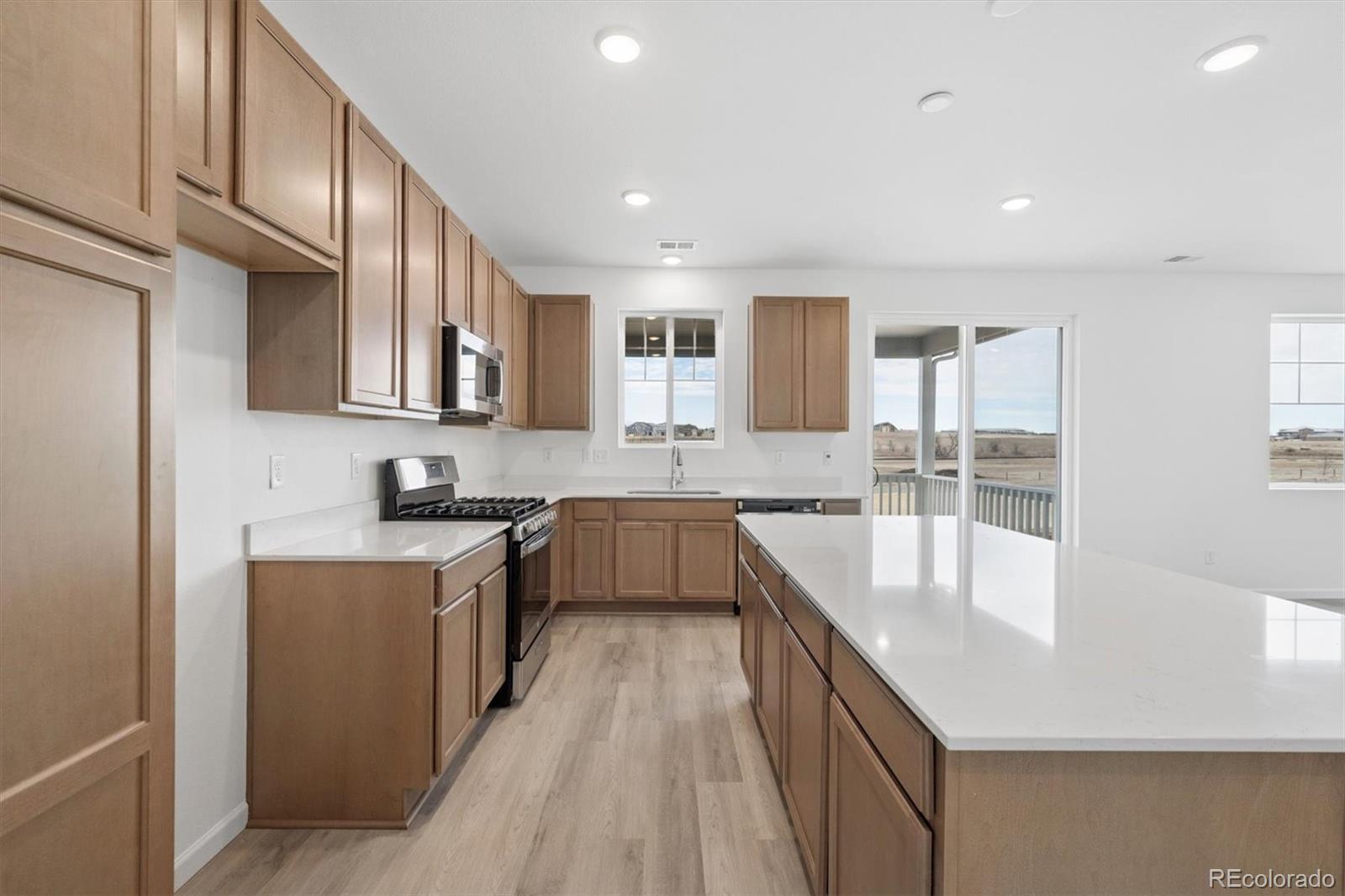 424 South Rifle Street Aurora, CO 80017 - Photo 6 of 23 a large kitchen with stainless steel appliances granite countertop a lot of counter space and wooden floors