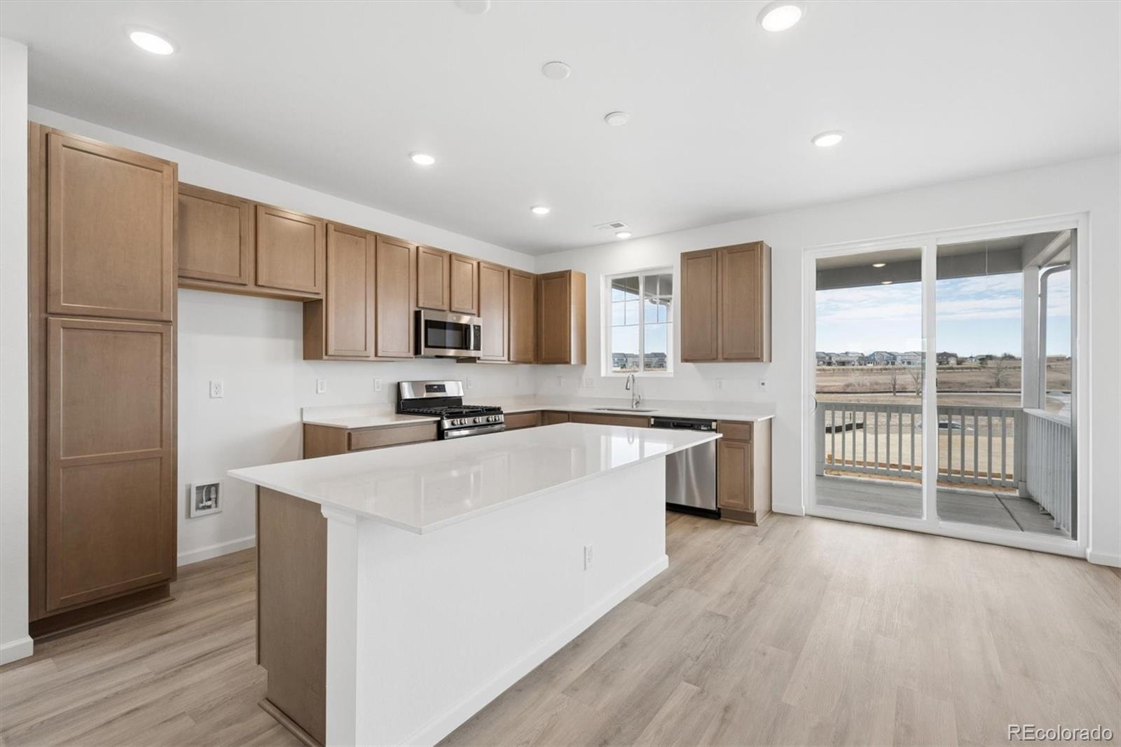424 South Rifle Street Aurora, CO 80017 - Photo 7 of 23 a large kitchen with stainless steel appliances granite countertop a stove a sink dishwasher a refrigerator and white cabinets with wooden floor