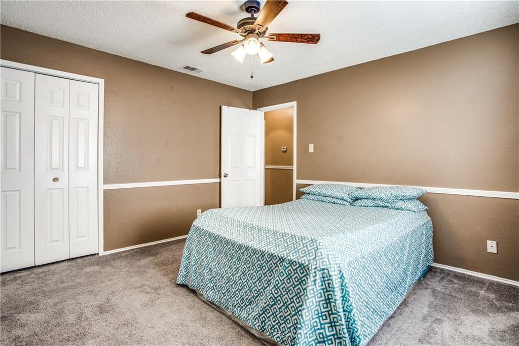 6817 Haltom Road Fort Worth, TX 76137 - Photo 12 of 25 Carpeted room featuring a ceiling fan with light fixture, neutral-toned walls with chair rail molding, and bi-fold closet doors