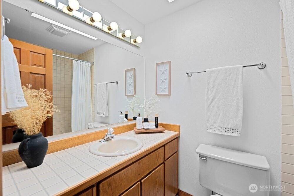 902 7th Avenue South Edmonds, WA 98020 - Photo 20 of 31 a bathroom with a granite countertop sink a toilet and a mirror