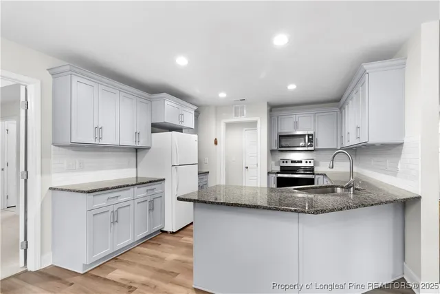 a kitchen with stainless steel appliances granite countertop a stove a sink and a refrigerator