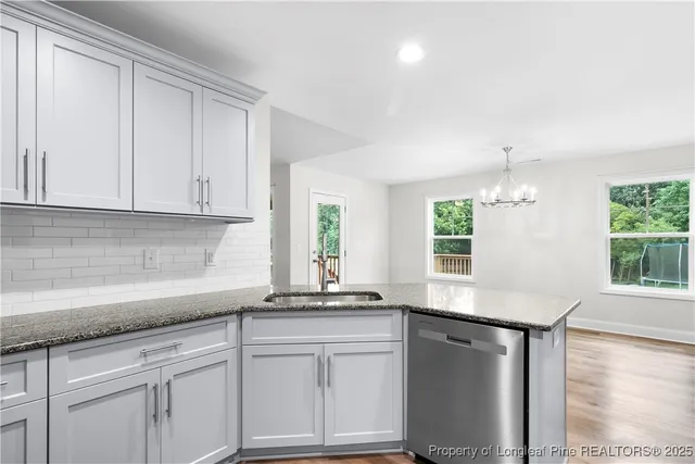 a kitchen with granite countertop white cabinets white appliances a sink and a window