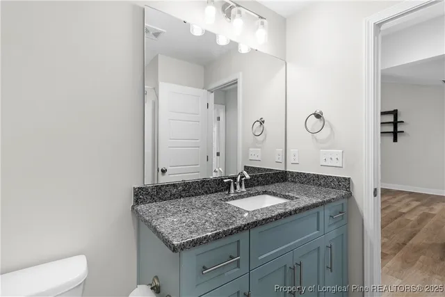 a bathroom with a granite countertop sink a toilet and a mirror