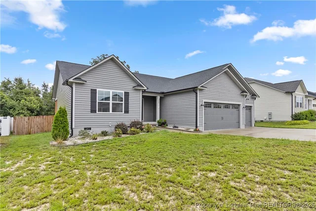 a front view of house with yard and trees in the background