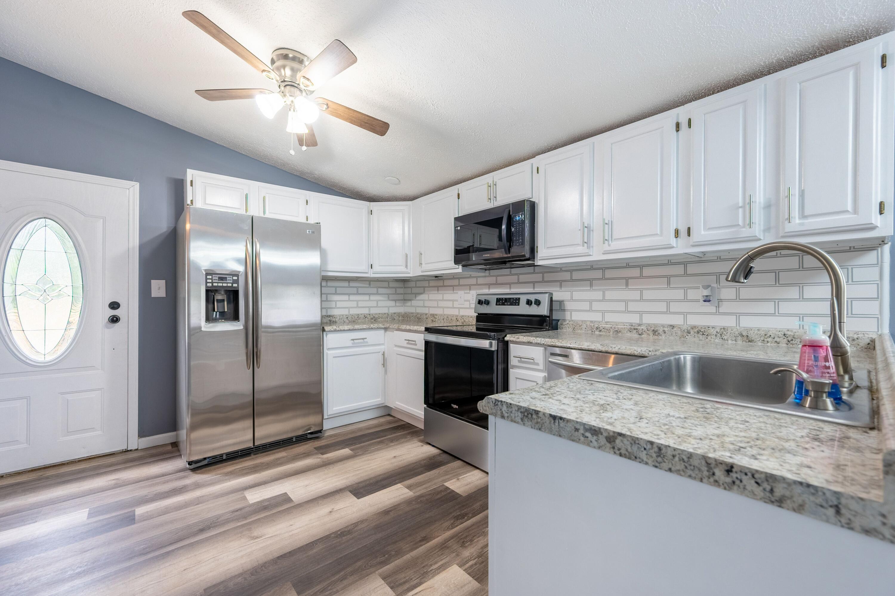 4342 County Line Road Patrick Springs, VA 24133 - Photo 18 of 34 a kitchen with granite countertop a refrigerator a sink a stove and cabinets