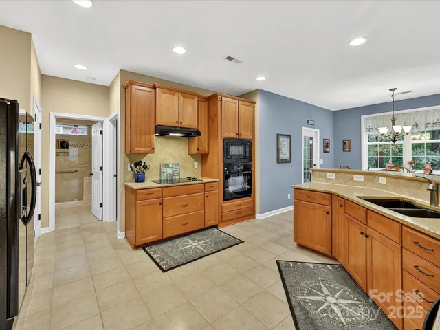 a large kitchen with stainless steel appliances kitchen island granite countertop a refrigerator and a stove top oven