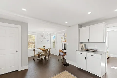 a kitchen with white cabinets and chairs