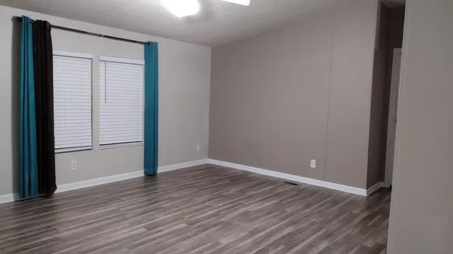 a view of an empty room with wooden floor and closet