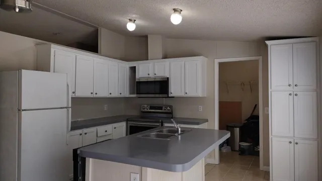 a kitchen with kitchen island a white counter top space cabinets and stainless steel appliances