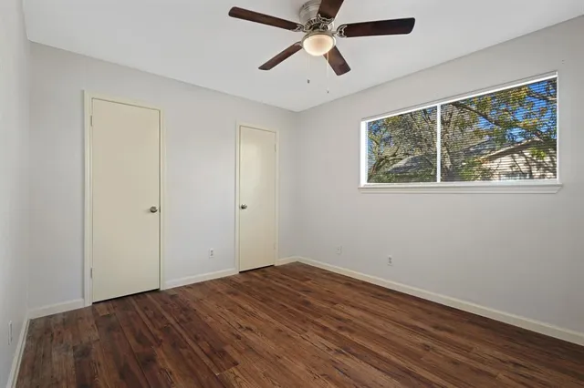 a view of empty room with wooden floor and fan