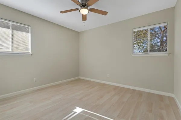 a view of an empty room with a window and a ceiling fan