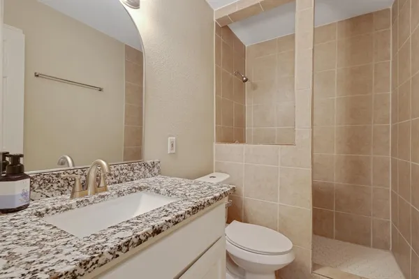 a bathroom with a granite countertop sink a toilet and shower
