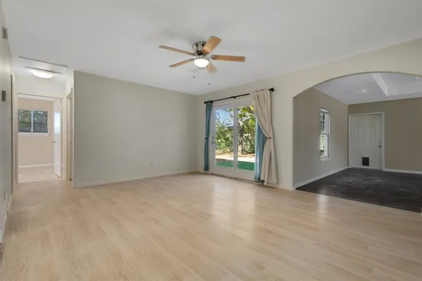a view of an empty room with window and wooden floor